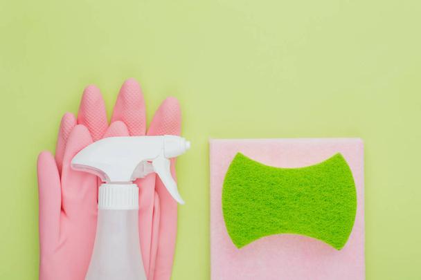 Concept modern minimalist cleaning and cleanliness, flat lay on a green background lime color lie pink rubber gloves and sprayer, rags and sponges, place for text - Zdjęcie, obraz