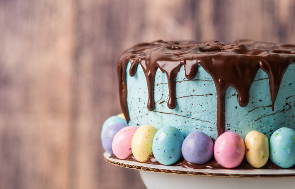Синий глазированный торт с шоколадной глазурью и пасхальными яйцами в ржавой обстановке
 - Фото, изображение