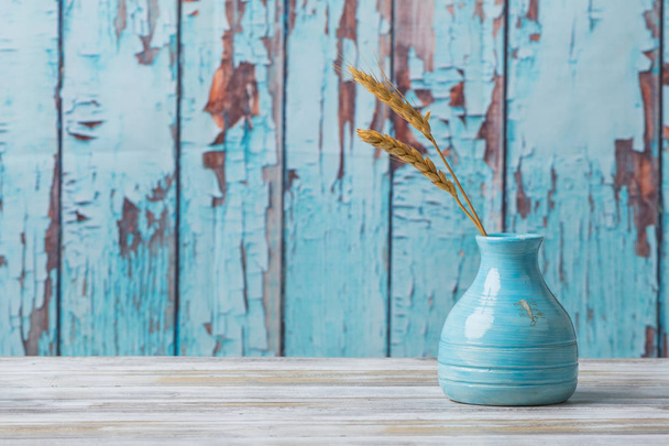Jarrón de cerámica azul con trigo sobre fondo de madera rústica
 - Foto, imagen