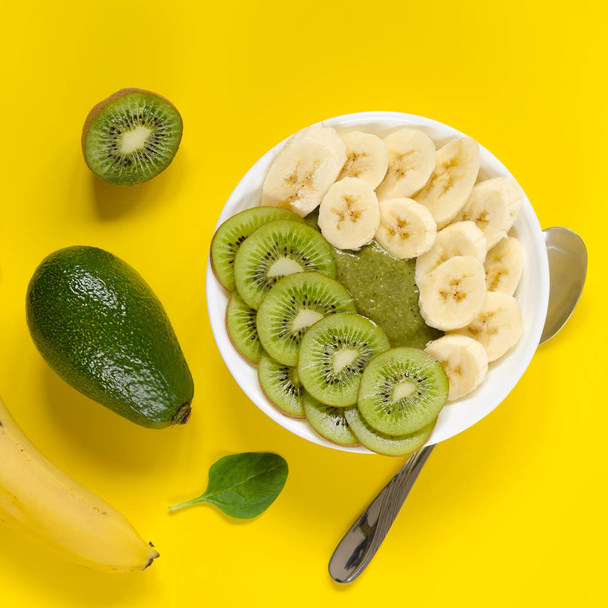 Green smoothie in a white bowl on yellow background - Фото, изображение