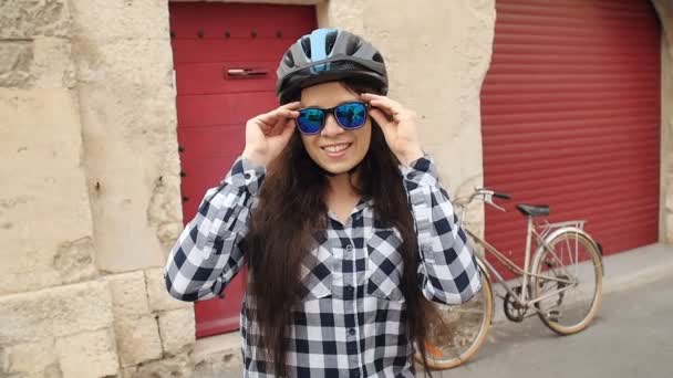 Młodych kobiet rowerzysta w okularach i w hełmie, uśmiechając się i patrząc na kamery - Materiał filmowy, wideo