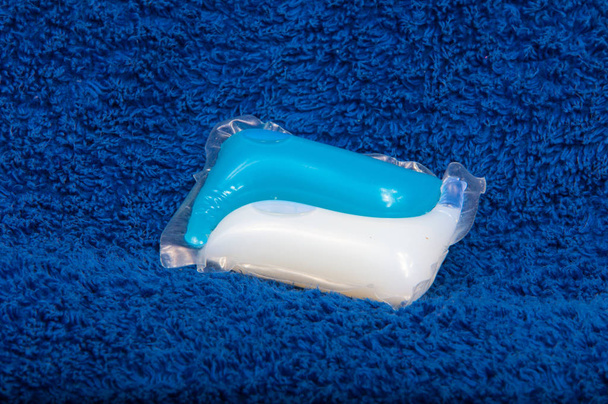Мойка цветной гелевой капсулы на синей текстуре ткани
 - Фото, изображение