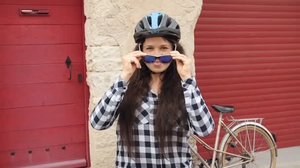 Joven ciclista femenina con gafas y un casco sonriendo y mirando a la cámara
 - Metraje, vídeo
