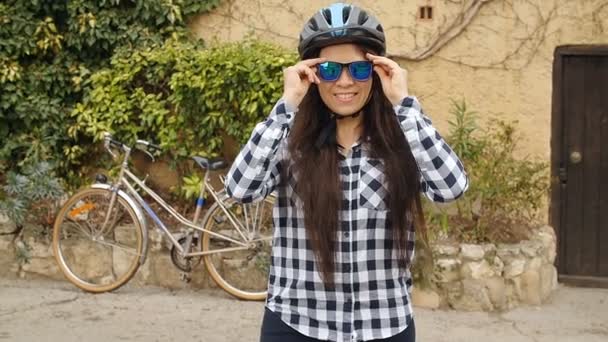 Jonge vrouwelijke fietser dragen van een bril en het dragen van een helm glimlachen en kijken naar camera - Video