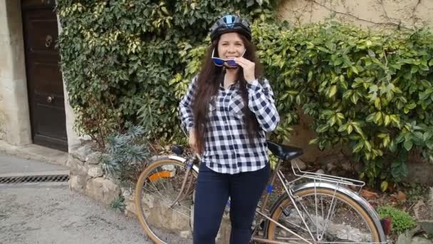 眼鏡と笑顔でカメラ目線のヘルメットを身に着けている若い女性の自転車 - 映像、動画