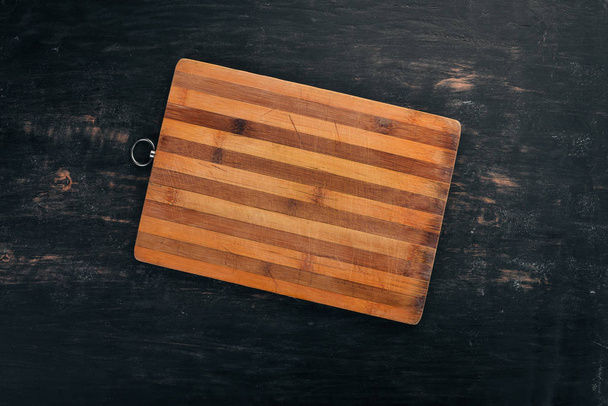 Kitchen cutting board. Top view. On a black wooden background. Copy space. - 写真・画像