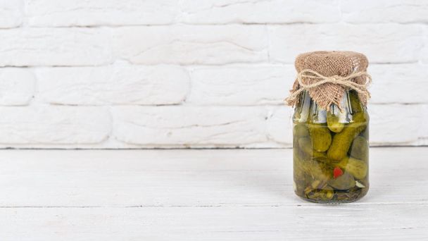 Pickled cucumbers in a jar. Stocks of food. Top view. On a wooden background. Copy space. - Photo, Image