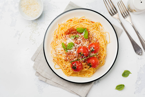 Traditional Italian dish of spaghetti with tomato sauce and parmesan cheese in ceramic plate on light concrete background. Selective focus. Top view. - Fotografie, Obrázek