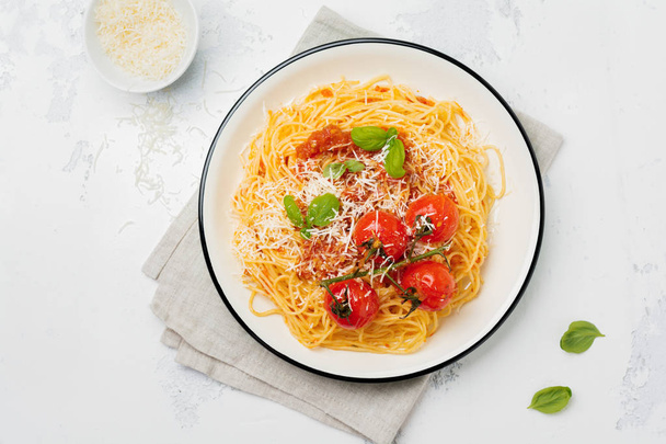 Traditional Italian dish of spaghetti with tomato sauce and parmesan cheese in ceramic plate on light concrete background. Selective focus. Top view. - 写真・画像