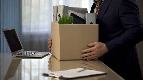 Employee putting his stuff from work desk in carton box, leaving job, retirement - 写真・画像