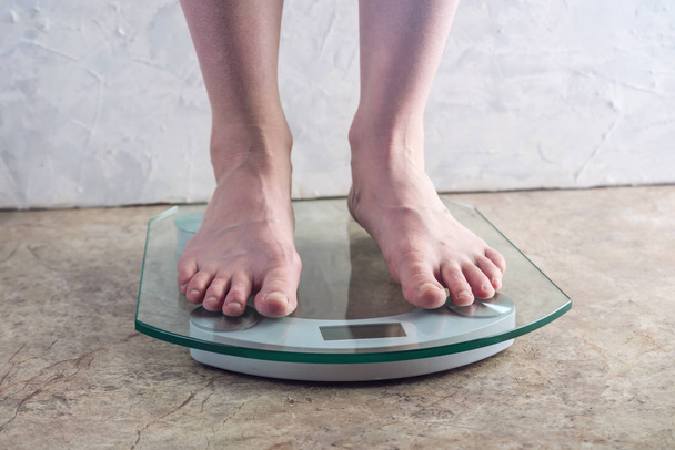 Female feet standing on electronic scales for weight control on light background. The concept of sports training, diets and weight loss - Photo, Image