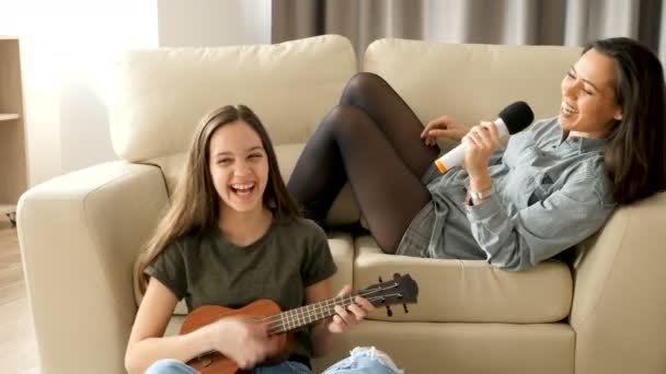 Młodsza i starsza siostra śpiewając w salonie - Materiał filmowy, wideo