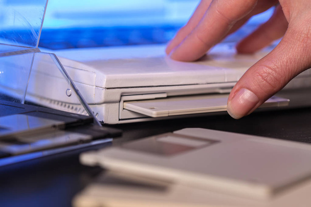 Insertion à la main d'une disquette dans un vieil ordinateur portable - gros plan
 - Photo, image