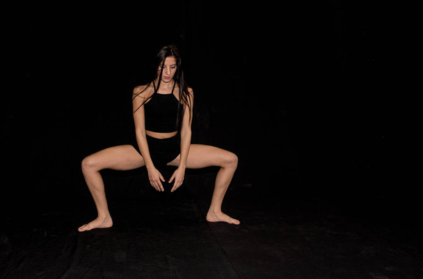 Expresiva bailarina contemporánea de ballet, bailando en el escenario con un fondo negro
. - Foto, imagen