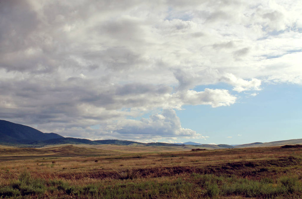 Estepa ancha con hierba amarilla bajo un cielo azul con nubes blancas Sayan montañas Siberia Rusia
 - Foto, imagen