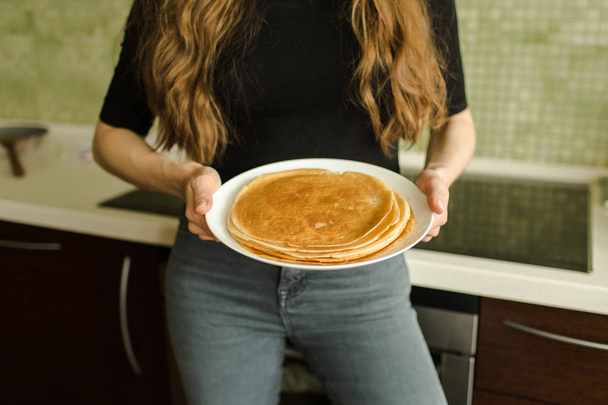 the woman is standing with pancakes in the kitchen - Photo, image