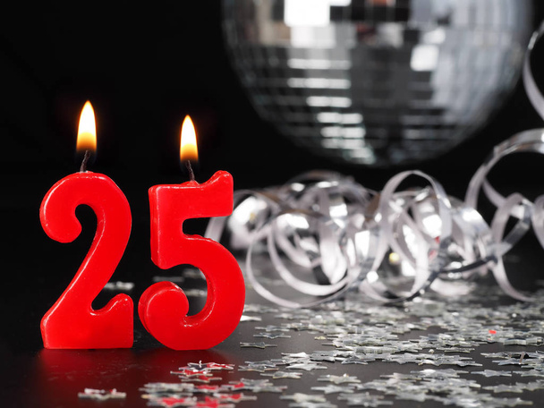 Nr。 25 を示す赤い蝋燭。誕生日や記念日のパーティーのための抽象的な背景. - 写真・画像