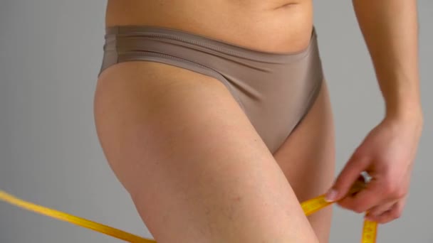 Kobieta mierzy jej nogi z taśma pomiarowa - Materiał filmowy, wideo
