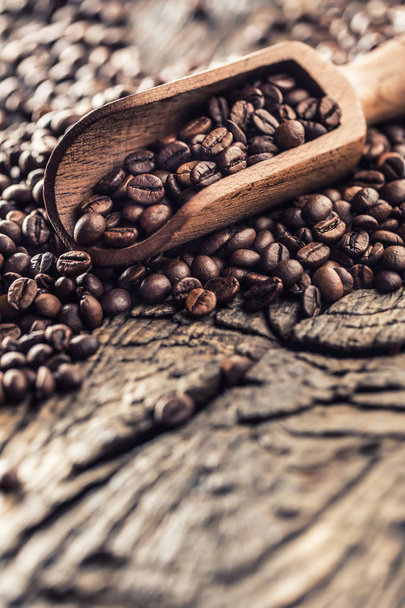Wooden scoop full of coffee beans on old oak table - Fotografie, Obrázek