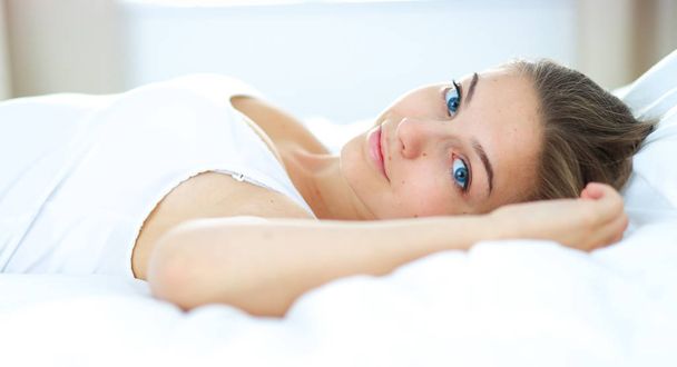 A beautiful young woman lying in bed comfortably and blissfully - Photo, Image