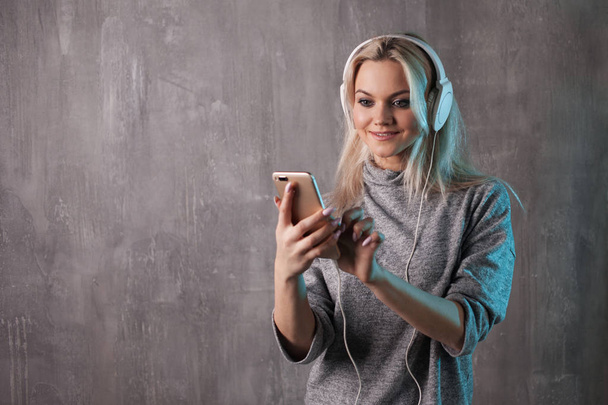 Charming young woman using smartphone and big earphones - Foto, Imagem