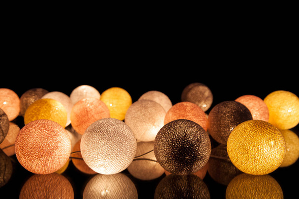 Colorful glowing balls on a black background. Glowing garland at night. Colorful circles on the background. - Photo, Image
