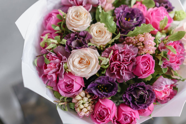 paarse en roze boeket van mooie bloemen op houten tafel. Bloemschikken concept. Lente kleuren. het werk van de bloemist op een bloemenwinkel. Verticale foto - Foto, afbeelding