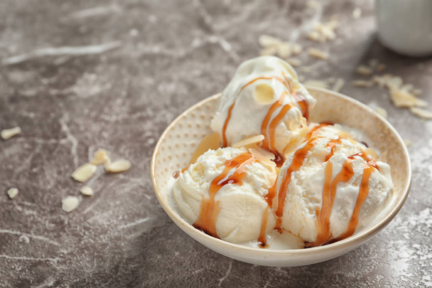 Tasty ice cream with caramel sauce in bowl on table - Photo, Image