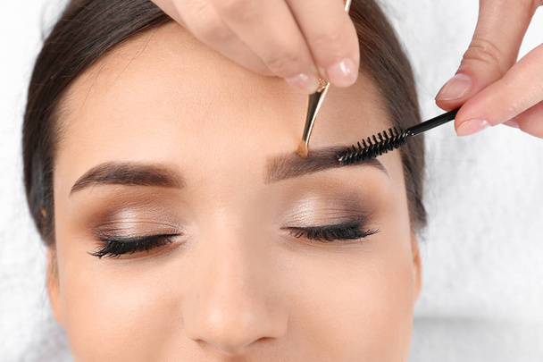 Young woman having professional eyebrow correction procedure in beauty salon - Zdjęcie, obraz