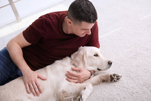 Handsome man with dog lying on carpet at home - Photo, Image