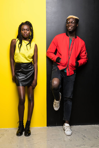 若くて色の背景上に分離されて幸せなアフロ アメリカン カップル。男と女アフロ アメリカンが黄色と黒に分離された楽しい時を過す - 写真・画像