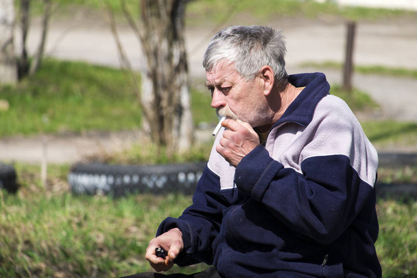 Homme barbu aux cheveux gris fumant une cigarette sans filtre
 - Photo, image