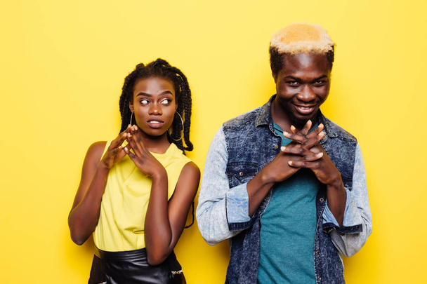 Muotokuva yllättynyt nuori afrikkalainen pari pukeutunut kesän vaatteita juhlii eristetty keltaisella taustalla
 - Valokuva, kuva
