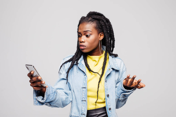 Young afro american woman Look and Writes on the Phone Isolated on a gray - Foto, Imagen