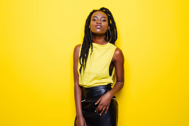 Szépség portré fiatal afro-amerikai lány pózol a sárga háttér, látszó-on fényképezőgép. - Fotó, kép