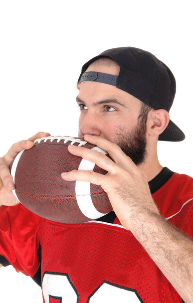 Jugador de fútbol sosteniendo su pelota en su boca pensando
 - Foto, Imagen