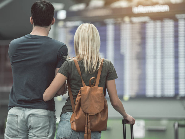 Girl and male watching at airport board - Valokuva, kuva