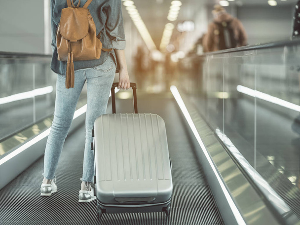 Woman holding luggage on moving stairs - Foto, Bild