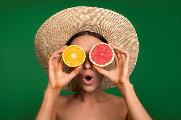 Lady in hat covering eyes with citrus - Foto, Bild