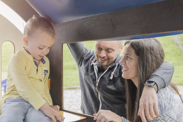 Родители веселятся со своим ребенком на детской площадке в парке
 - Фото, изображение