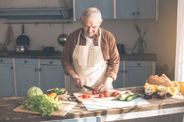 Calm mature male pensioner cooking healthy breakfast - 写真・画像