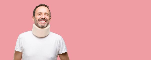Injured senior man using a neck brace confident and happy with a big natural smile laughing - Photo, Image