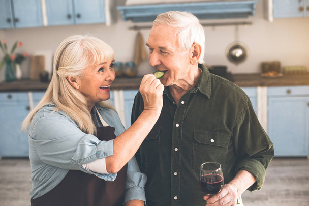 Excited pensioners tasting healthy vegetable in cook room - 写真・画像