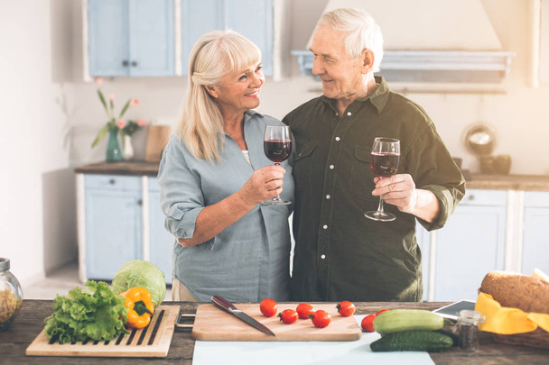 Cheerful senior man and woman enjoying romance in cook room - Foto, afbeelding