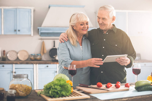 Glad senior husband and wife preparing healthy food in kitchen - Фото, изображение