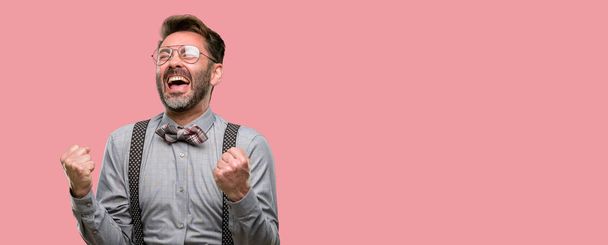 Middle age man, with beard and bow tie happy and excited expressing winning gesture. Successful and celebrating victory, triumphant - Photo, Image
