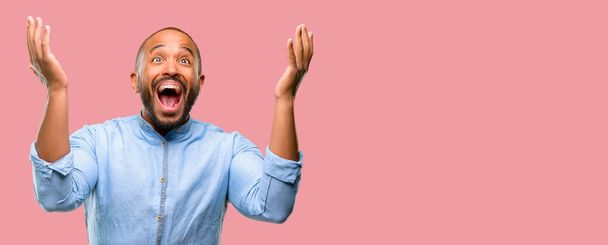Uomo afroamericano con la barba felice e sorpreso tifo esprimendo gesto wow
 - Foto, immagini