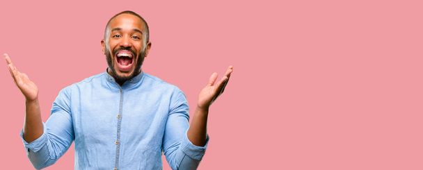 Hombre afroamericano con barba feliz y sorprendido vitoreando expresando un gesto de sorpresa
 - Foto, Imagen