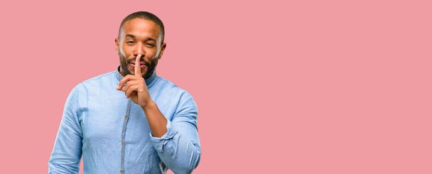 Afrikanisch-amerikanischer Mann mit Bart und Zeigefinger auf den Lippen, bitte um Ruhe. Schweigen und geheimes Konzept - Foto, Bild