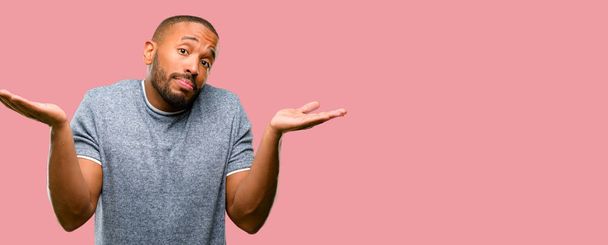 Африканский американец с бородой выражает сомнение, путает и удивляется концепции, неопределенное будущее пожимая плечами
 - Фото, изображение